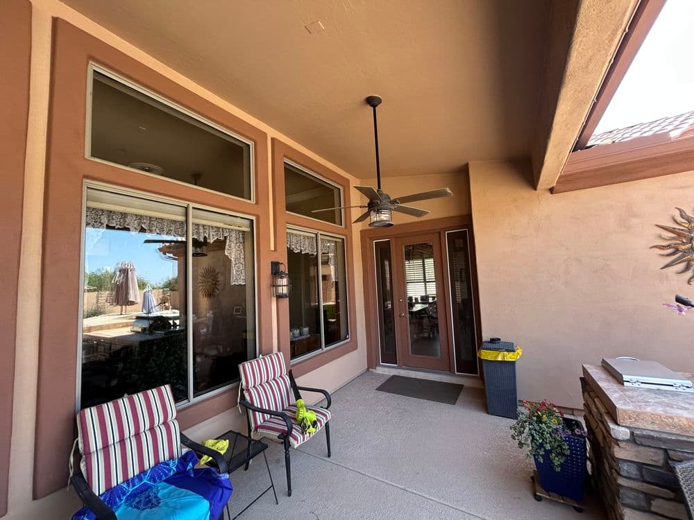 Patio area with striped chairs, ceiling fan, and sliding doors leading to outdoor space.